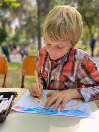 Little blond boy drawing open air lesson