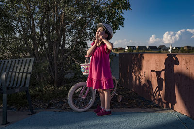 Girl removing bicycle helmet while standing at park