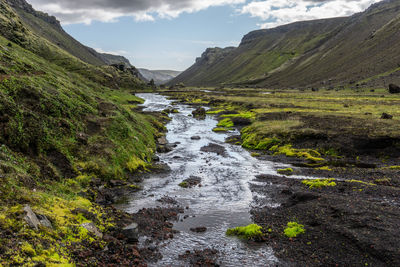 Scenic view of river flowing amidst mountains against sky