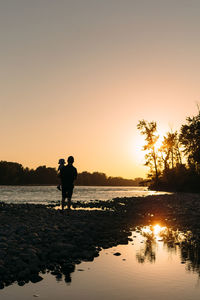 Silhouette man standing on beach against clear sky during sunset