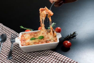 Close-up of hand holding pizza on table