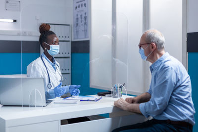 Doctor wearing mask examining patient in clinic