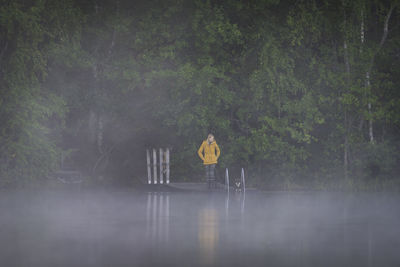 People standing by tree in lake during rainy season