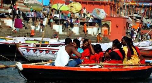 People sitting in boat on canal against buildings