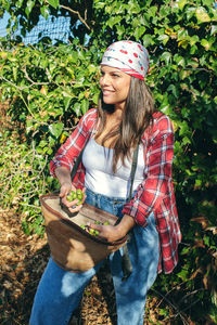 Young woman holding ice cream standing against plants