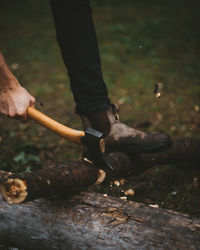 Low section of man cutting wood in forest