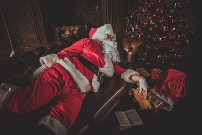 Man wearing santa claus costume sleeping on sofa at home