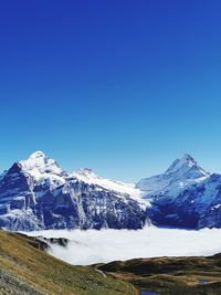 Scenic view of snowcapped mountains against clear blue sky