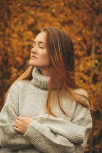 Young woman with eyes closed standing in park during autumn