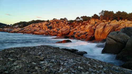 Scenic view of rocks in sea against clear sky