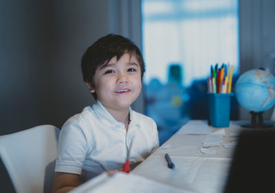 Portrait of smiling boy sitting on table