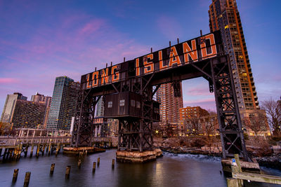 Bridge over river in city at sunset