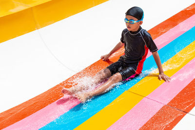 Boy sitting on slide at water park