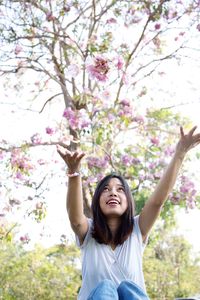 Low angle view of happy woman catching purple flowers 