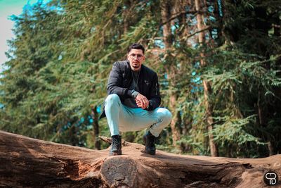 Young man sitting on rock in forest