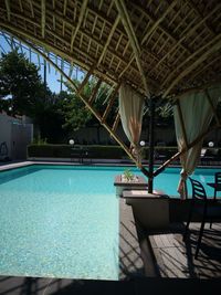 Chairs and tables in swimming pool against trees