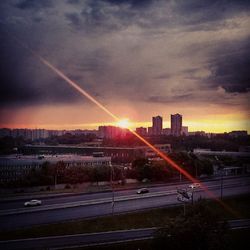 Sun shining through clouds over city