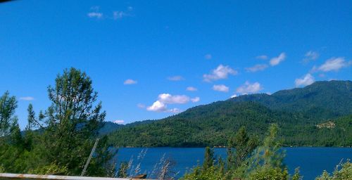 Scenic view of lake and mountains against blue sky