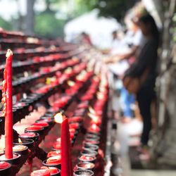 Close-up of illuminated candles in temple against building