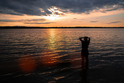 Silhouette person standing on beach against sky during sunset