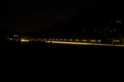 Illuminated street by buildings in city at night