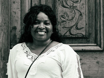 Portrait of smiling woman standing against closed door