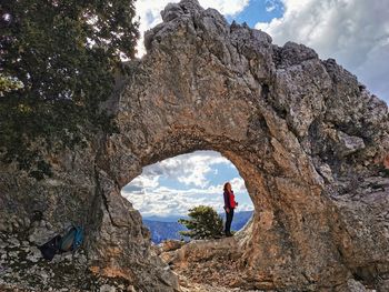 Man standing on rock against sky