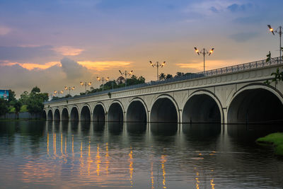 Arch bridge over lake against sky during sunset