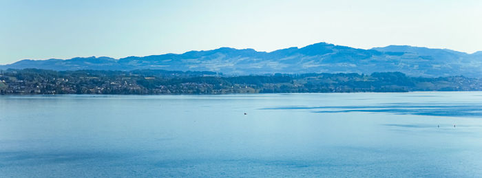 Scenic view of sea and mountains against clear sky