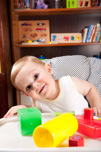 Portrait of cute baby boy playing with toys on table at home