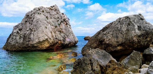 Rock formation in sea against sky