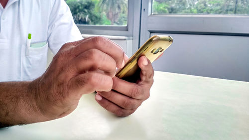 Midsection of man holding smart phone on table