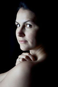 Close-up portrait of young woman against black background