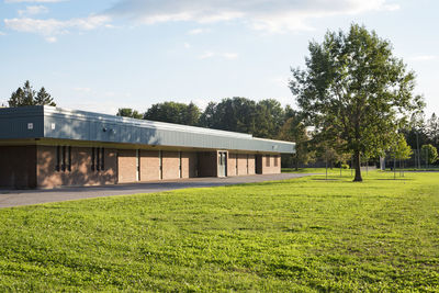 Built structure on field by trees against sky