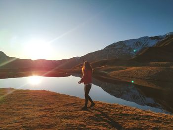 PERSON STANDING ON MOUNTAIN AGAINST SKY