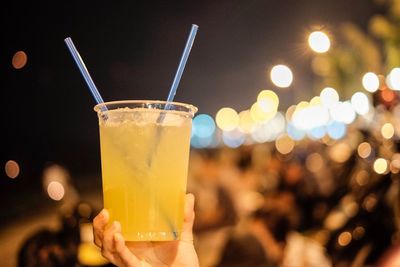 Cropped hand holding drink glass at night
