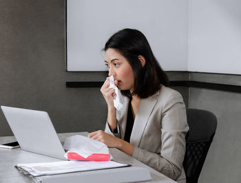 Young woman using mobile phone while sitting on table