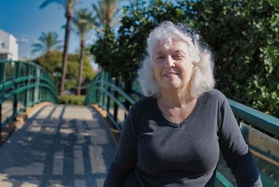 Portrait of a smiling gray-haired lady on a pedestrian bridge. copy space.