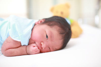 Portrait of baby girl lying on bed at home