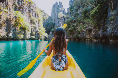 Rear view of woman kayaking in sea