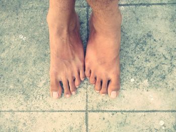 Low section of man standing on tiled floor