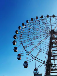 Low angle view of ferris wheel against clear blue sky