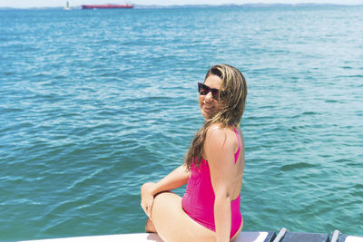 A woman on top of a boat against the sea in the background. 