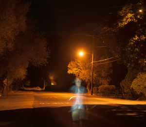 Empty road along trees at night