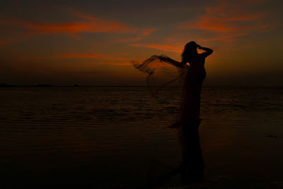 Silhouette person standing at beach during sunset