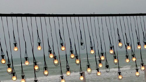 Low angle view of illuminated lights hanging against sky