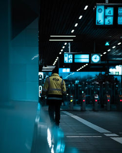 Rear view of man walking on illuminated city at night