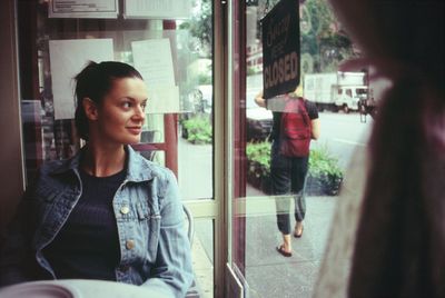 Portrait of young woman looking through window