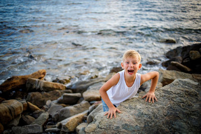 Portrait of smiling girl on rock at sea shore