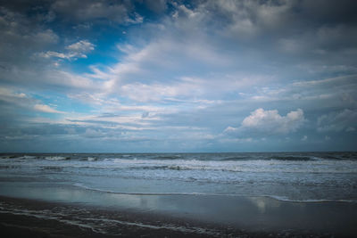 Scenic view of beach against cloudy sky